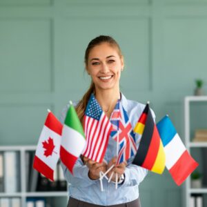 Happy female tutor showing bunch of diverse flags, recommending foreign language studying school