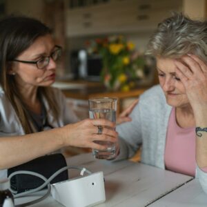 Healthcare worker or caregiver visiting senior woman indoors at home, explaining