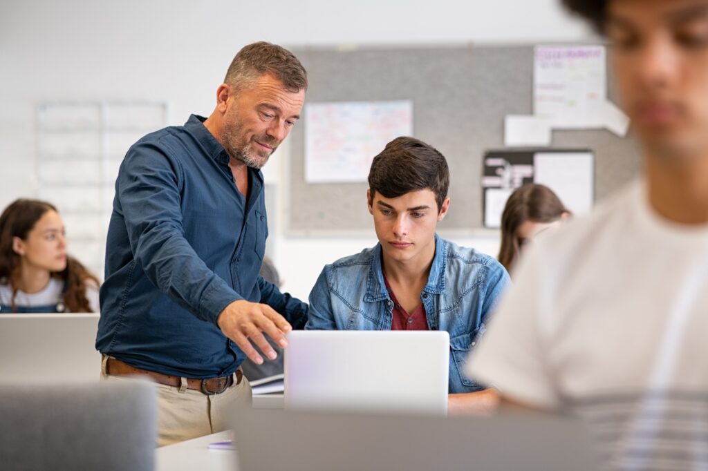 Professor helping student during computer class